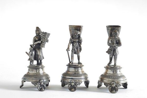 Tre figurine in metallo argentato portafiori su base circolare piedini a ricciolo