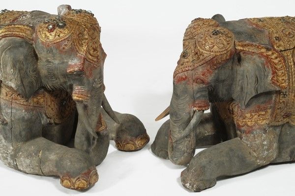 Coppia di sculture in legno di elefanti accucciati con finimenti dorati e inserti in vetro, Sud-e...